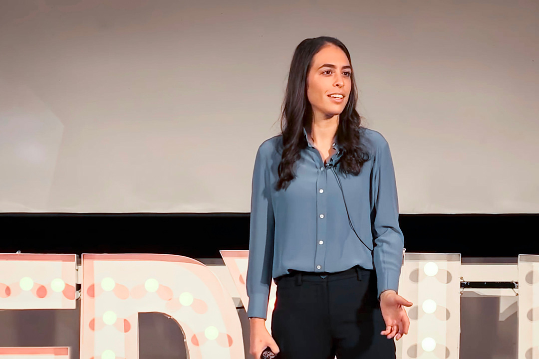 Fallon Goodman stands on stage and presents her TED Talk