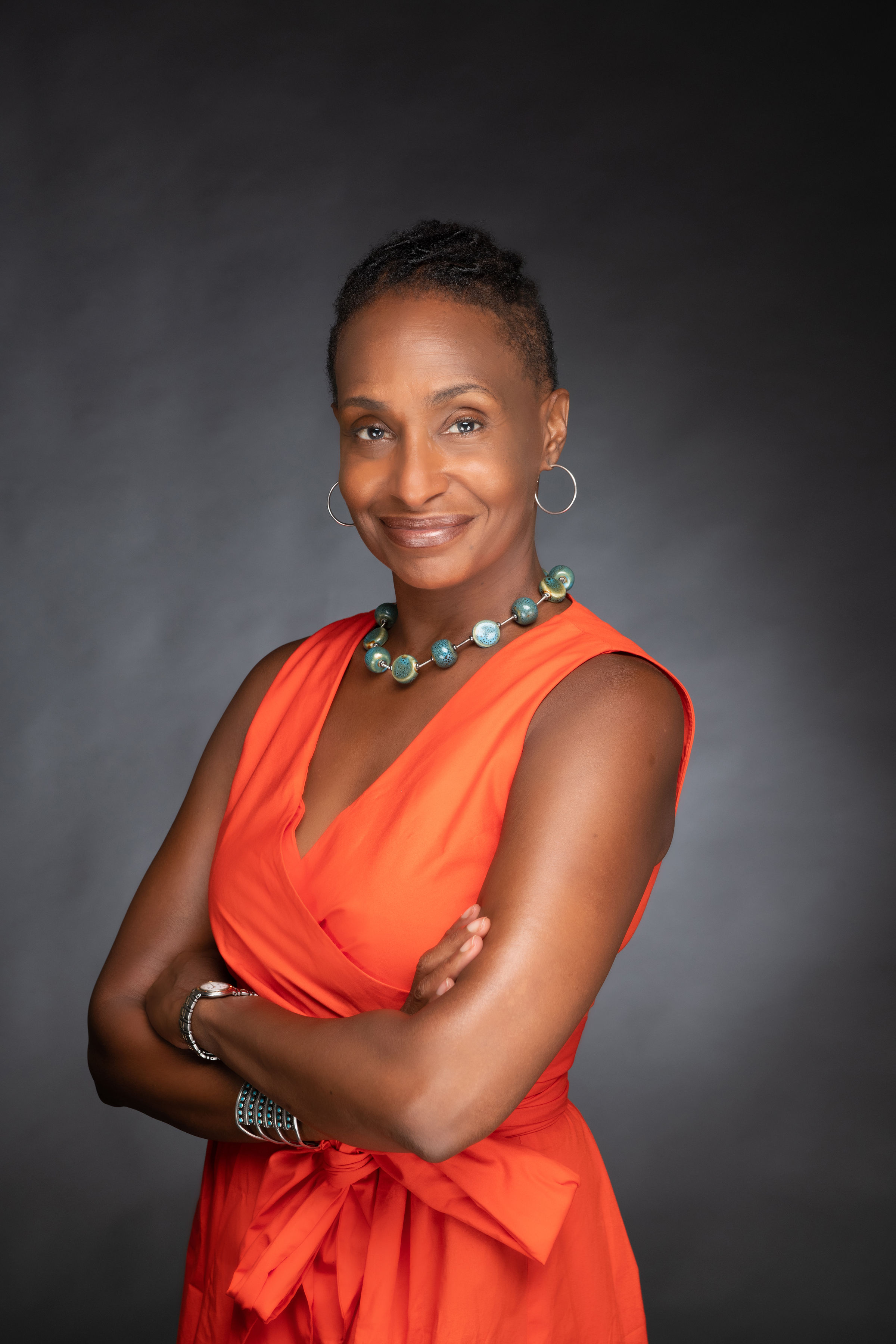 Bowleg standing in an orange outfit with her armed crossed