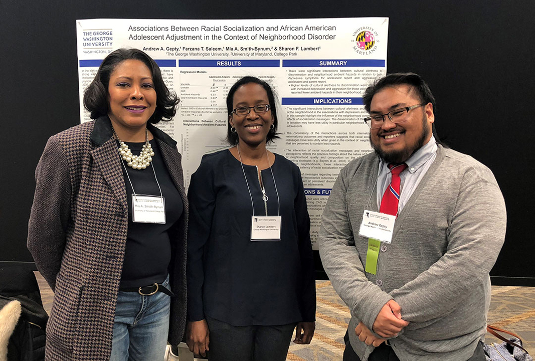 Professor Mia Smith-Bynum stands with two students in front of their research presentation.