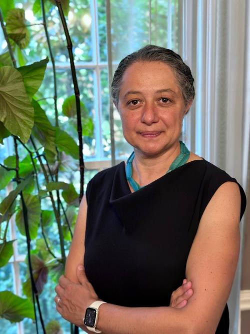 Sarah Shomstein standing next to a window with a potted plant