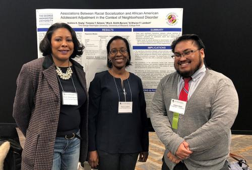 Professor Mia Smith-Bynum stands with two students in front of their research presentation.