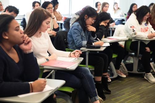 Group of students sitting at desks listening to a psychology professor