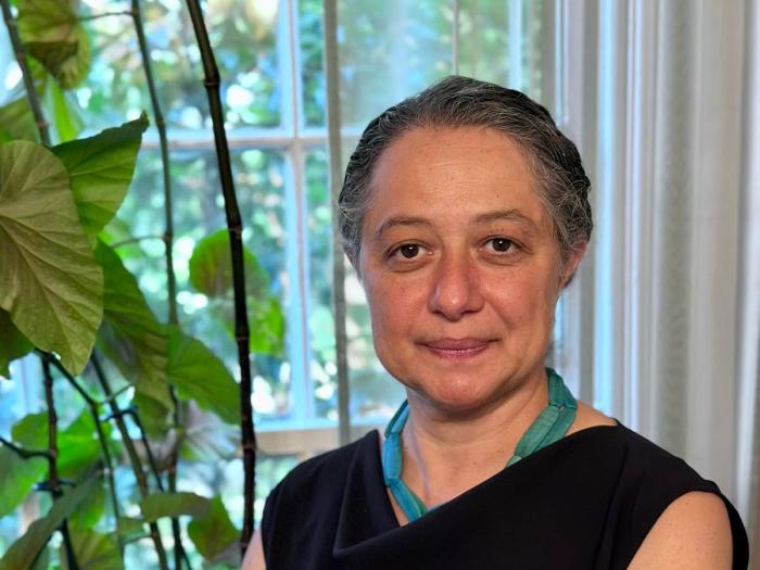 Sarah Shomstein standing next to a window with a potted plant